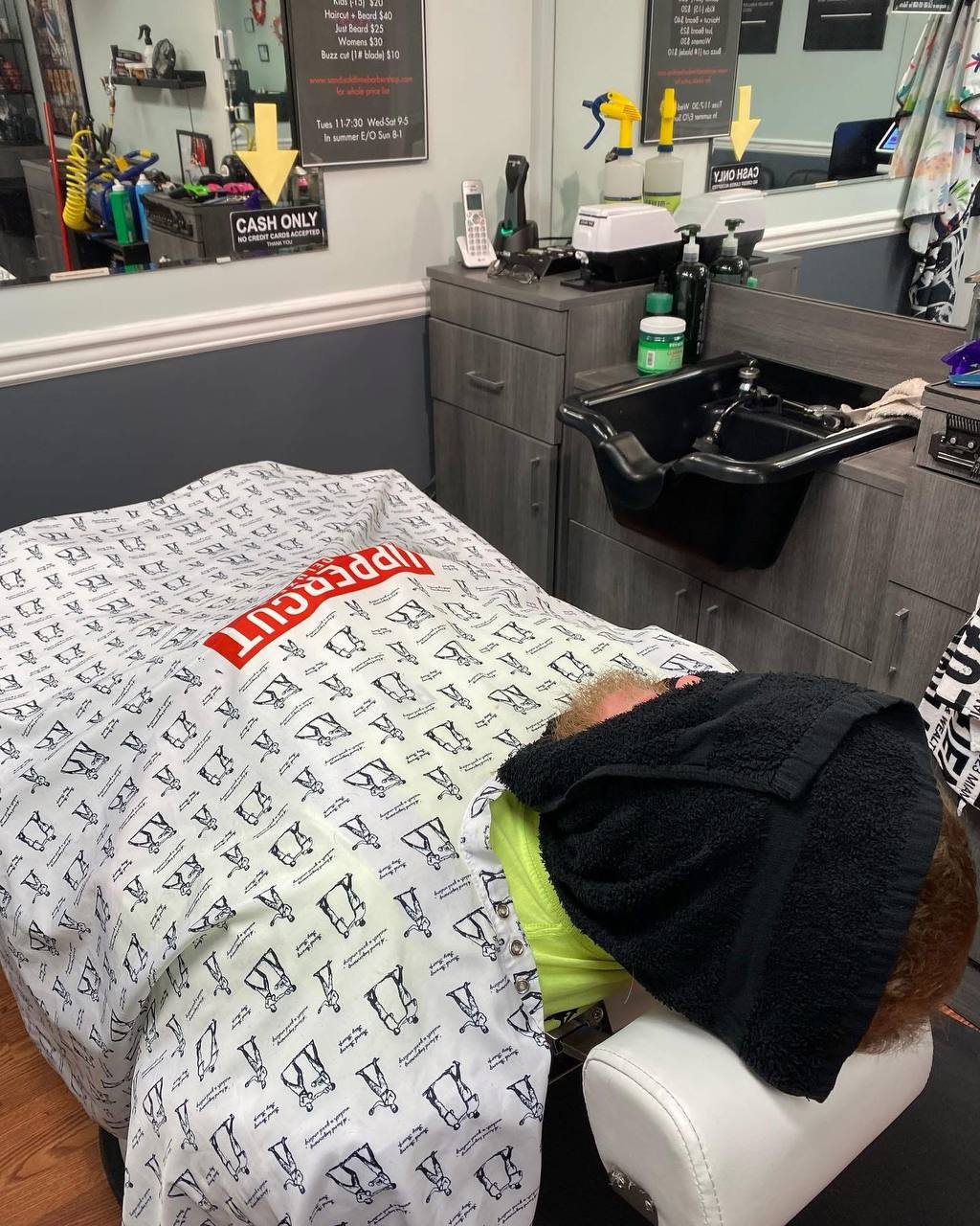 A client reclined with a hot towel on the face at Sandi's Old Time Barbershop